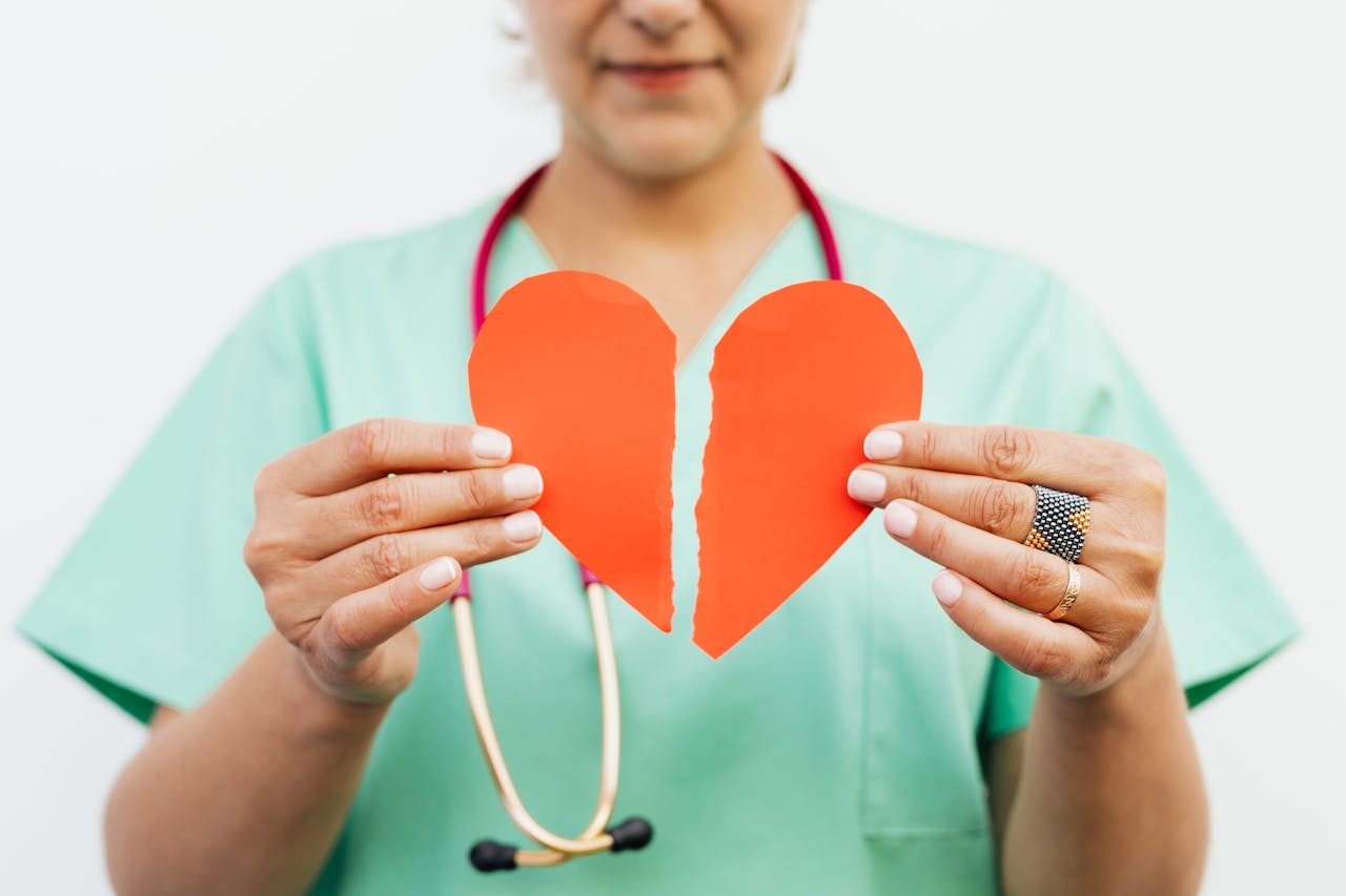 Nurse holding a torn paper heart symbolizing emotional or heart health care.